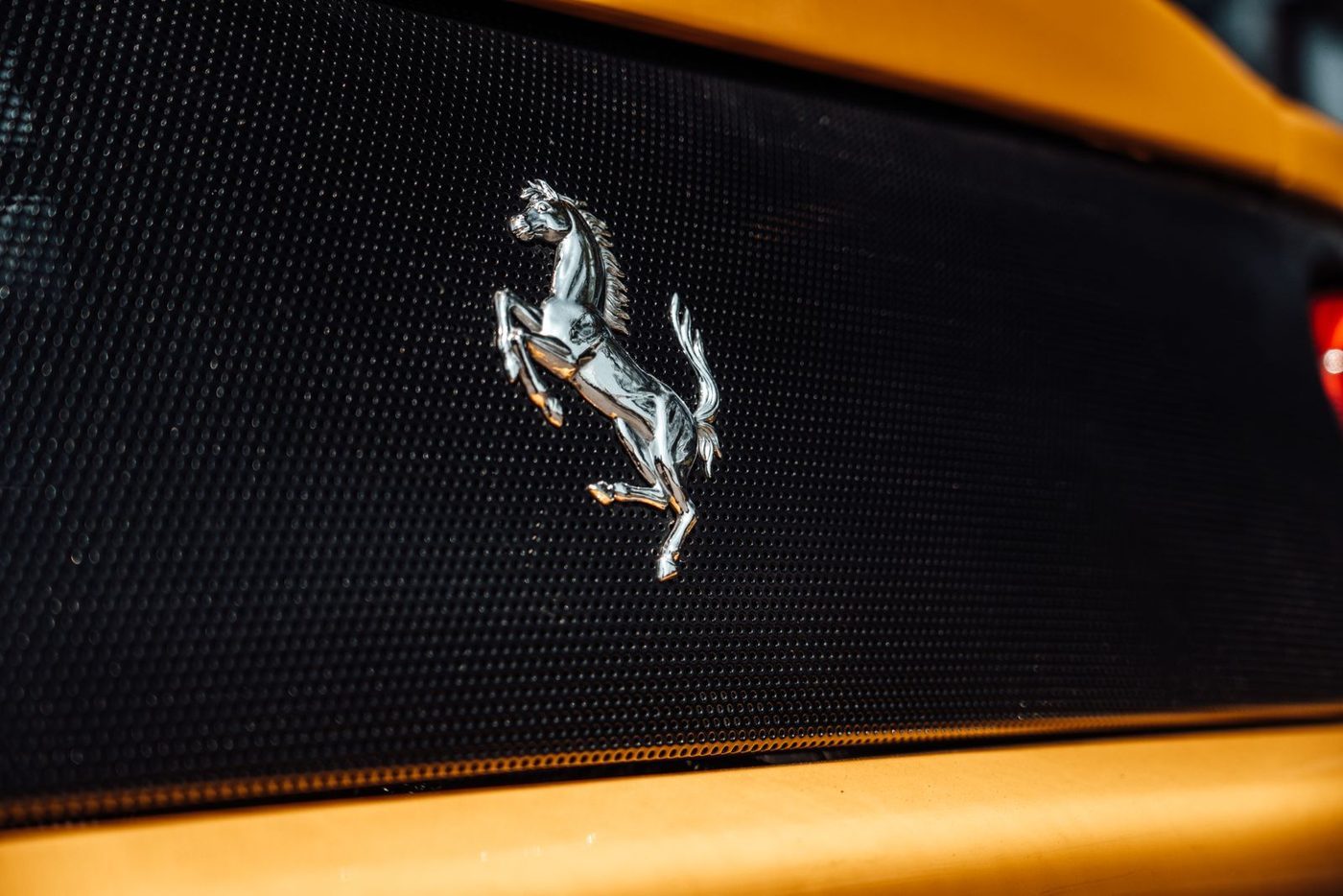 Ferrari prancing horse badge on the grille of a yellow car